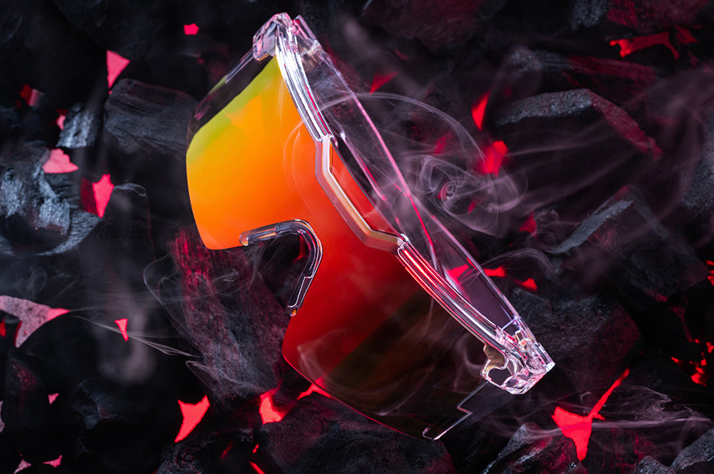 Close up of Heat Wave Future Tech Vapor Clear Sunblast safety sunglasses with hot bbq coals behind them.