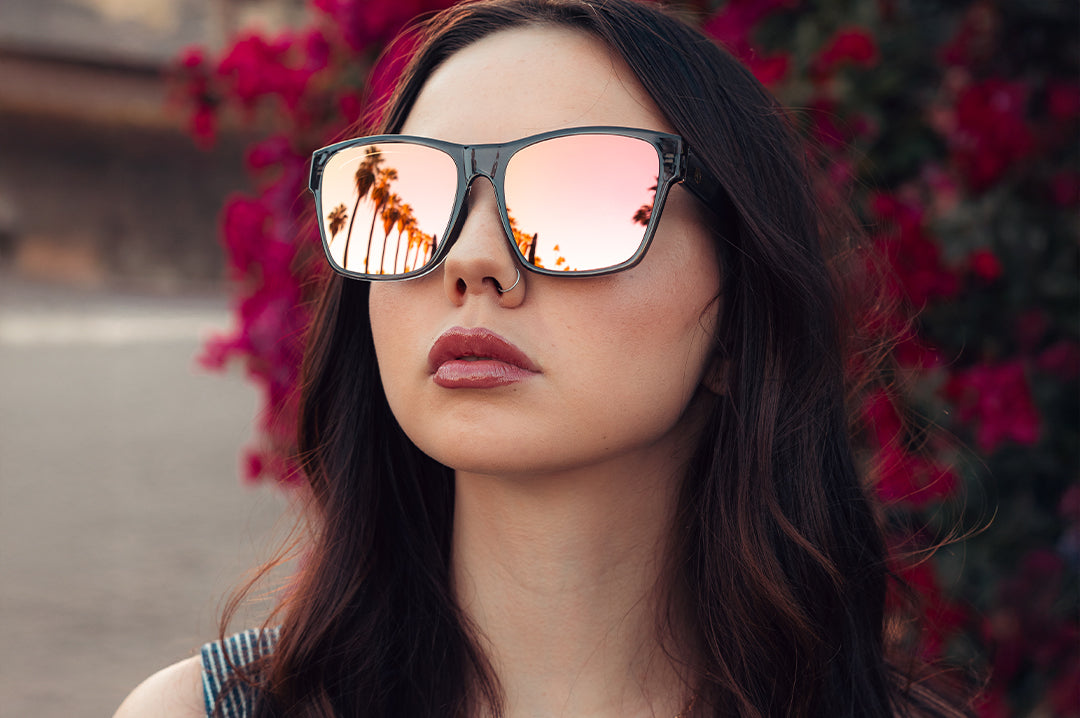 Young woman walking in through the streets wearing the Heat Wave Visual Marylin Sunglasses with quartz frames and rose gold lenses.