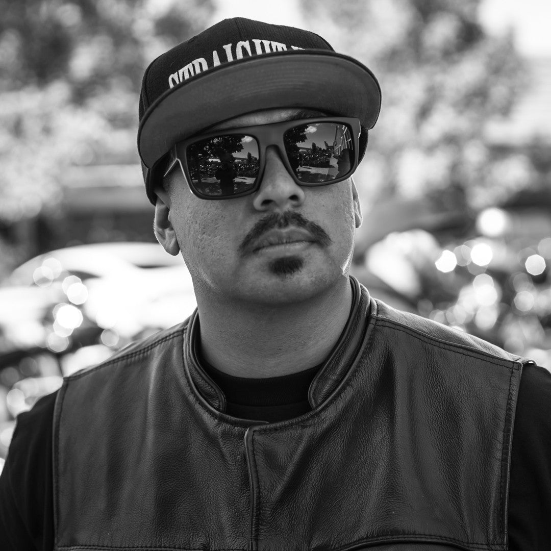 Motorcyclist in club vest wearing Heat Wave Visual Regulator Sunglasses with black frame and black lenses.